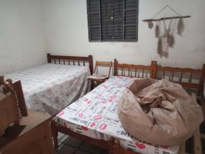 a bedroom with two beds and a table and a window at Casa com piscina perto da praia in São Sebastião +4 photos