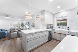 a kitchen with white cabinets and a living room at SOBE Retreat - Designers Dream - Fenced backyard in Jacksonville Beach