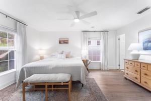 a white bedroom with a bed and two windows at SOBE Retreat - Designers Dream - Fenced backyard in Jacksonville Beach