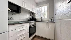 a white kitchen with a sink and a refrigerator at Bungalow Playa Poniente Benidorm in Benidorm