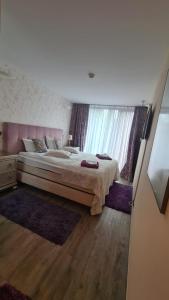- une chambre avec un grand lit et une grande fenêtre dans l'établissement Penthouse Silver Mountain, Duplex 3 camere - 250 mp luxury garden - Poiana Brasov, à Braşov