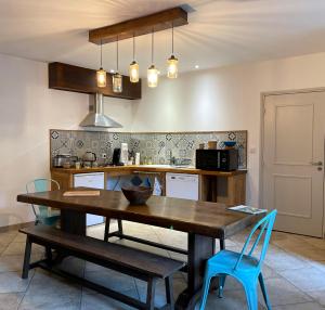 uma cozinha com uma mesa de madeira e cadeiras azuis em Chambre d'Aut' em Autun