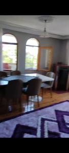 a dining room with a table and chairs and two windows at Beyaz hostel in Trabzon
