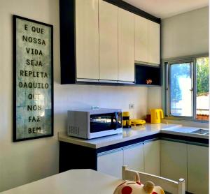 uma cozinha com armários brancos e um micro-ondas no balcão em Casinha da Rena em Cambury em São Sebastião
