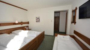 a bedroom with two beds and a flat screen tv at Gästepension Hermann Arnold in Sölden