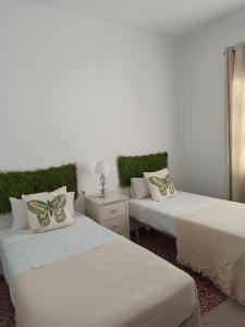 2 camas en una habitación con plantas verdes en REVUELTAS Apartments, en Carmona