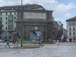 ミラノにあるAppartamento Porta Romanaの通りを横断する人々のいる街路の石造りの建物