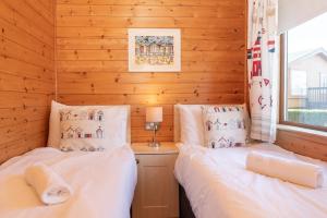 two beds in a room with wooden walls at 28 Ocean Terrace Lodge - Mullacott Park in Ilfracombe