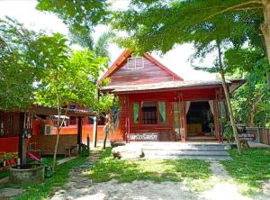 uma pequena casa vermelha com árvores em frente em ต้นพร้าวรีสอร์ท Ton prao Resort 