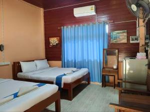 um quarto com duas camas e uma tv nele em ต้นพร้าวรีสอร์ท Ton prao Resort 