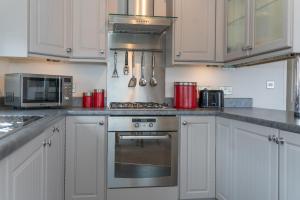 a kitchen with white cabinets and a stove top oven at 46 Meadow View in Woolacombe