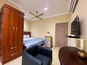 a bedroom with a bed and a tv and a chair at Royal Riverside Lodge in Big Ada