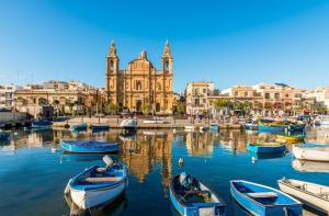 a group of boats in the water in front of a building at Blue Waves Apartment with Maltese Balcony in Valletta