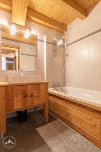 a bathroom with a sink and a tub and a mirror at Le Marteen’s appartement pour 6 personnes à Val Cenis in Lanslebourg-Mont-Cenis