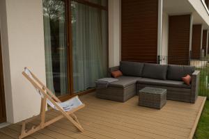 a patio with a couch and a chair on a porch at Apartament Sand & Sun in Sianozety