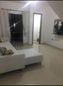 um sofá branco numa sala de estar com uma porta em Lindo Apartamento a beira Mar- Praia do Muta em Porto Seguro