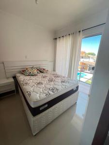 Cama en habitación con ventana grande en Lindo Apartamento a beira Mar- Praia do Muta en Porto Seguro