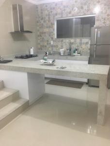 a kitchen with a counter with a sink and a refrigerator at Lindo Apartamento a beira Mar- Praia do Muta in Porto Seguro
