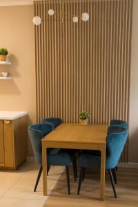 a dining room table with blue chairs and a curtain at Apartament Sand & Sun in Sianozety