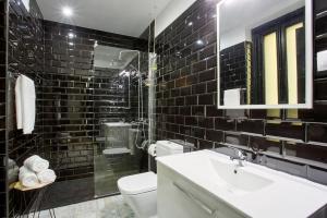 a black tiled bathroom with a sink and a toilet at SERRANO GOLDEN MILE, by Presidence Rentals in Madrid