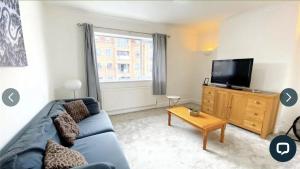 a living room with a blue couch and a tv at 4 bedroom property which sleeps 8 very close to the Harry Potter studio and Watford junction in Leavesden Green