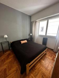 a bedroom with a large black bed in a room at Departamento Las Heras in Mar del Plata