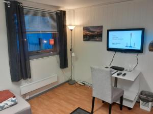 a room with a desk with a television and a chair at Wilhelmsen Romutleie in Vardø