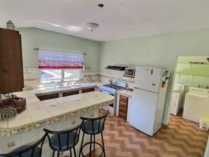 a kitchen with a white refrigerator and some chairs at Mountain View Family Home In Town With King Suite in San Ignacio