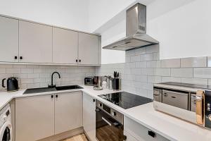 倫敦的住宿－Contemporary Oasis in Paddington II，白色的厨房设有水槽和炉灶。