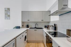 a white kitchen with a sink and a dishwasher at Contemporary Oasis in Paddington II in London