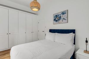 a bedroom with a white bed with a blue headboard at Contemporary Oasis in Paddington II in London