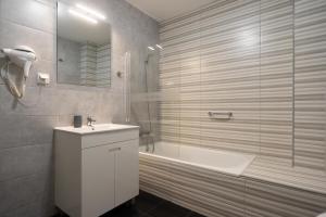 a bathroom with a tub and a sink and a shower at Leevin Guesthouse in Faro