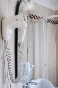 un sèche-cheveux suspendu sur un mur à côté d'un miroir dans l'établissement Hotel Villa Serena, à Marghera