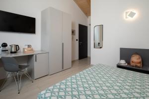 a bedroom with a bed and a desk and a television at Theodore Rooms in San Teodoro