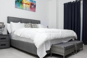um quarto com uma cama com lençóis brancos e uma cadeira em A307 Luxury 1 Bedroom em Acra
