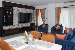 sala de estar con mesa, sillas y TV en A307 Luxury 1 Bedroom en Accra