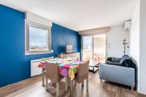 una sala da pranzo con tavolo, sedie e parete blu di Le Mayflower a Le Grau-du-Roi
