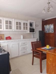 a kitchen with white cabinets and a table with chairs at Love Den in Christ Church