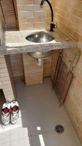 a bathroom with a sink and two pairs of shoes at Lindo Apartamento em Bertioga/SESC a 300m da praia in Bertioga