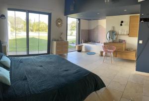 een slaapkamer met een bed en een badkamer met een bad bij Villa avec Pool House au cœur des vignes - Lubéron in La Tour-dʼAigues