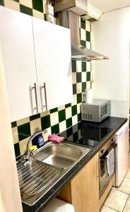 a kitchen with a sink and a microwave at Ground Floor One Bed Studio In London in London