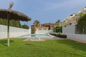 un patio con piscina y sombrilla en Bungalow con encanto, en San Juan de Alicante