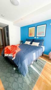 1 dormitorio con 1 cama grande y pared azul en Luxury NEW Apt -24/7 sec- 10 min from SJO Airport, en Heredia
