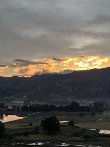 a sunset over a field with a lake and mountains at FINCA VILLA DEL CARMEN in Sibaté