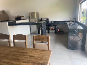 a kitchen with a counter with chairs and a table at Casa Jardim Primavera in Cunha