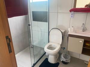 a bathroom with a toilet and a glass shower at Casa Jardim Primavera in Cunha