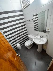 uma casa de banho com um lavatório, um WC e um espelho. em Hotel Reycer em Piura