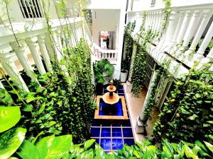 a person sitting on a bench in a room with plants at Hotel AT THE PARK in Cartagena de Indias