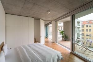 a bedroom with a large white bed and a balcony at Carlotta Apartments in Berlin +70 photos