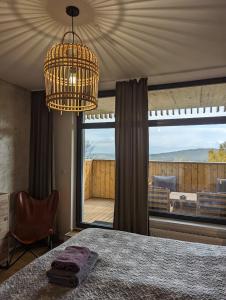 ein Schlafzimmer mit einem Kronleuchter und einem großen Fenster in der Unterkunft Zadov - Apartmán Srdce Šumavy in Stachy